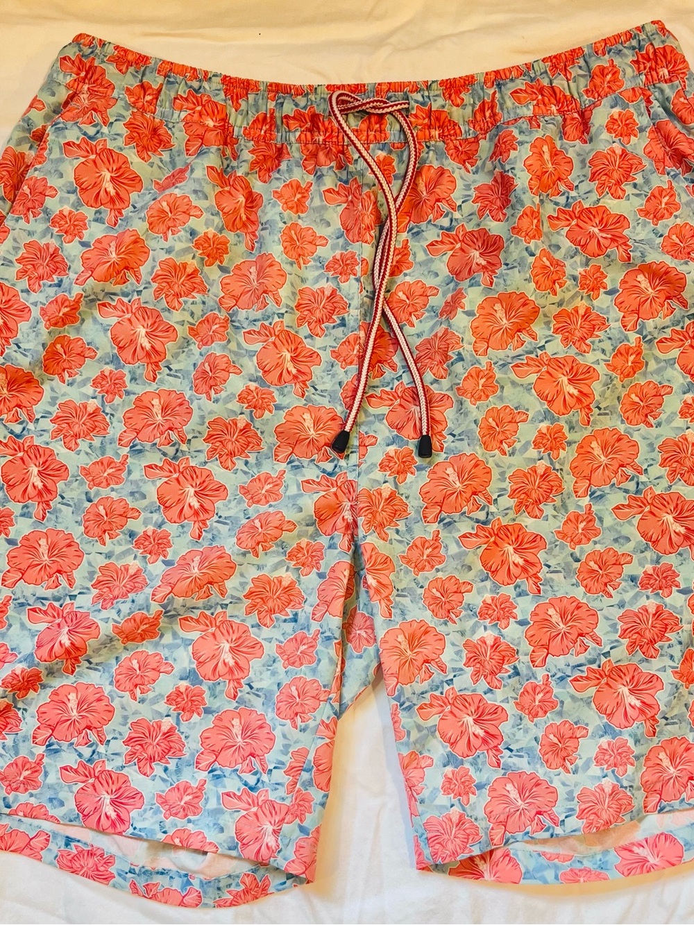 Peter Millar Coral Floral Swim Trunks with Light Blue Background